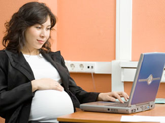 Trabajadora embarazada frente a su computadora